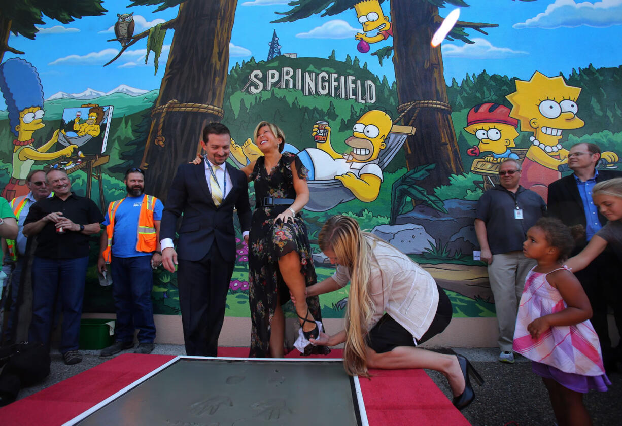 Actor Yeardley Smith, center, has her shoe wiped off after making her footprints in cement during the unveiling of the new &quot;The Simpsons&quot; mural in Springfield, Ore., on Monday.