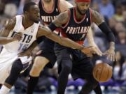 Charlotte Bobcats' Kemba Walker, left stretches to make a steal from Portland Trail Blazers' Mo Williams, right as Portland Trail Blazers' Robin Lopez watches from behind during the first half of an NBA basketball game in Charlotte, N.C., Saturday, March 22, 2014.