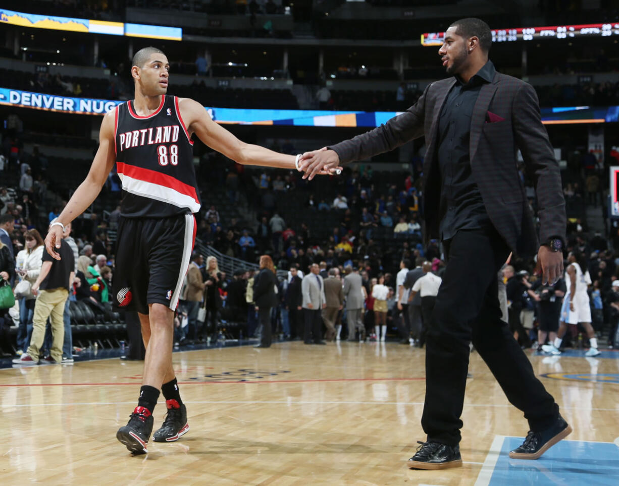 Portland Trail Blazers forward Nicolas Batum, left, of France, is congratulated by injured forward LaMarcus Aldridge after an NBA basketball game in Denver, Tuesday, Feb. 25, 2014. Portland won 100-95.