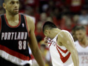 Houston Rockets' Jeremy Lin (7) wipes his face after the Rockets were called for a foul as Portland Trail Blazers' Nicolas Batum (88) walks down the court during the fourth quarter in Game 2 of an opening-round NBA basketball playoff series Wednesday, April 23, 2014, in Houston. Portland won 112-105. (AP Photo/David J.