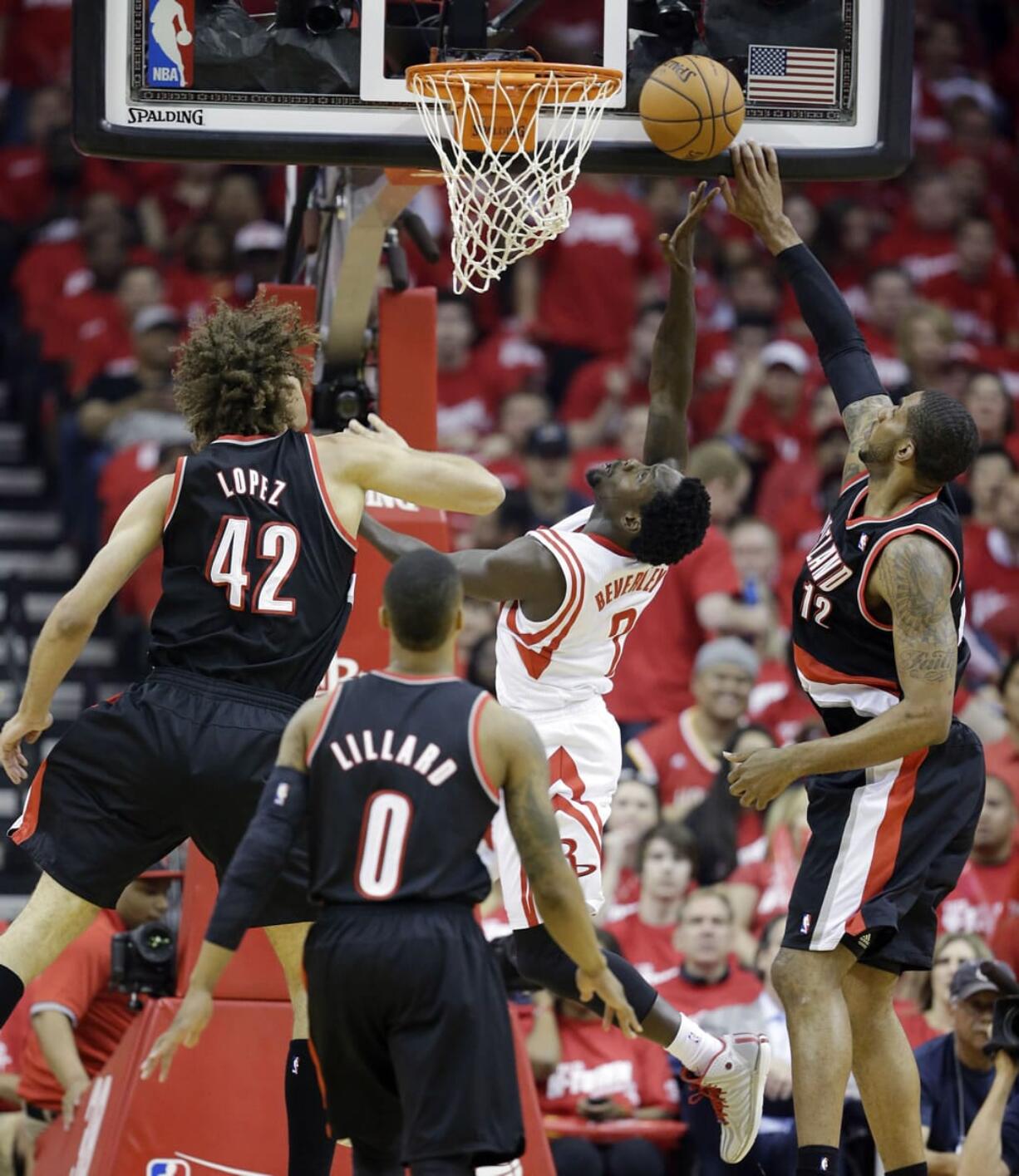 Houston Rockets' Patrick Beverley has a shot blocked as he drives against Portland Trail Blazers' LaMarcus Aldridge (12) and Robin Lopez (42) during the first half Sunday. (AP Photo/David J.