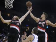 Portland Trail Blazers' Chris Kaman, left, and Meyers Leonard (11) reach for a rebound over Golden State Warriors' David Lee during the first half on Thursday, April 9, 2015, in Oakland, Calif.