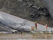 Survey crews in boats look over tanker cars as workers remove damaged tanker cars along the tracks where several CSX tanker cars carrying crude oil derailed and caught fire along the James River near downtown Lynchburg, Va., Thursday, May 1, 2014.  Virginia state officials were still trying Thursday to determine the environmental impact of the train derailment.