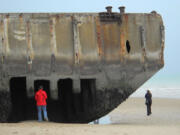 A visitor inspects the remains of an artificial harbor used by Allied forces during World War II on the sand at Arromanches, France.