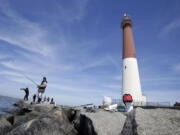 FILE - This April 30, 2013 file photo shows people fishing near the Barnegat Lighthouse on Long Beach Island, N.J. The Jersey shore is full of spots to drop a baited line or a wire trap over the side of a bulkhead, and come up with a bucket full of tasty blue claw crabs. Theyire biting now and will be through the end of September. And the beaches and jetties are prime surf-fishing spots after the lifeguards pack up and leave in the evenings.