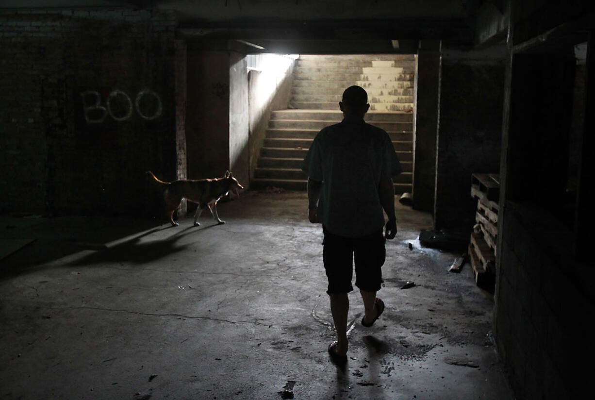 Caretaker Tristan Kempton and his watchdog, Ruger, make rounds inside the historic Tumwater Brewery in Tumwater, Wash., on Wednesday, May 14, 2014.  A new partnership wants to redevelop the historic brewhouse in Tumwater and restore the site's original purpose: Brewing beer. Referred to as the Craft Brewing and Distilling Center, the proposal was announced  May 15, 2014 as a key step in transforming the vacant area into an economic hub that generates jobs and tourism. The project targets the historic brewery properties north of Custer Way that are owned by Centralia-based developer George Heidgerken. Located next to the Deschutes River, the old brewhouse was part of Olympia Brewery, which closed in 2003 after nearly 100 years of making beer.