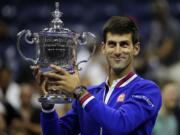 Novak Djokovic, of Serbia, holds up the championship trophy after beating Roger Federer, of Switzerland, in the men's championship match of the U.S. Open tennis tournament, Sunday, Sept. 13, 2015, in New York.