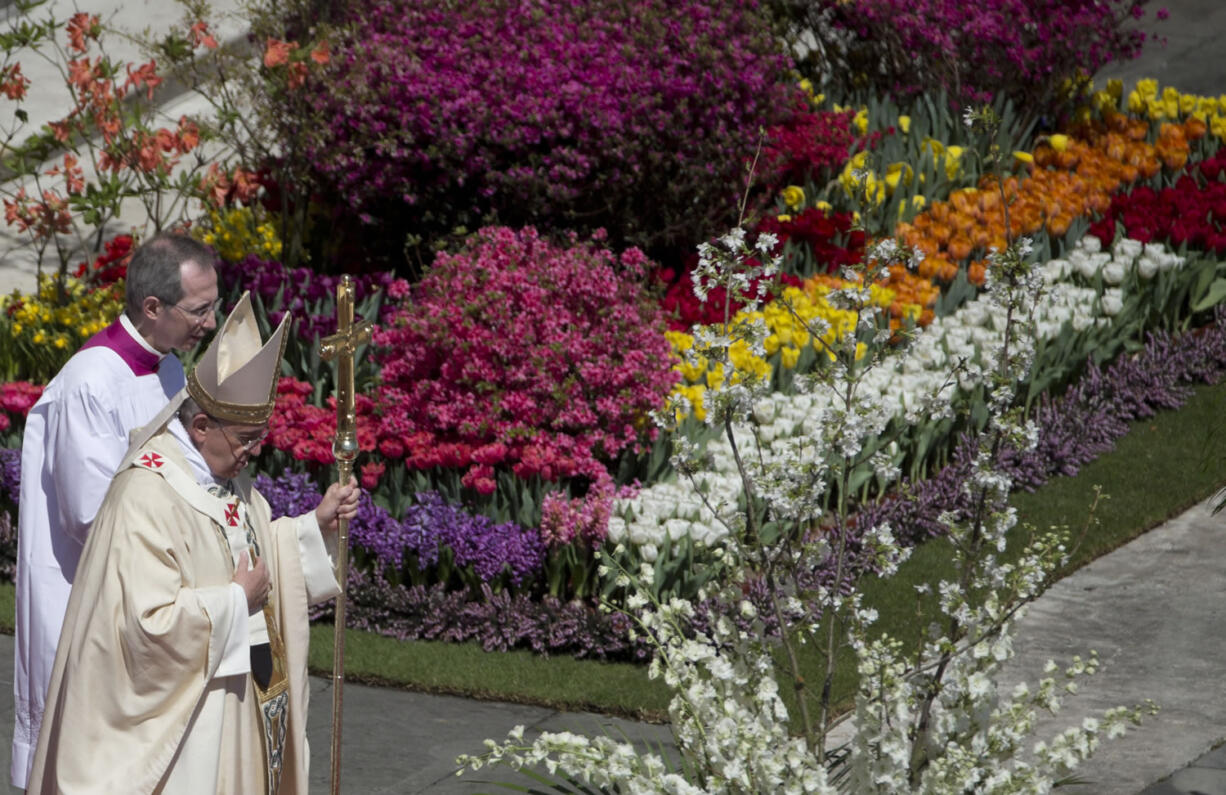 Pope Francis walks past decorative flowers as he leaves Sunday after celebrating an Easter Mass in St. Peter's Square, at the the Vatican.