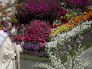 Pope Francis walks past decorative flowers as he leaves Sunday after celebrating an Easter Mass in St. Peter's Square, at the the Vatican.