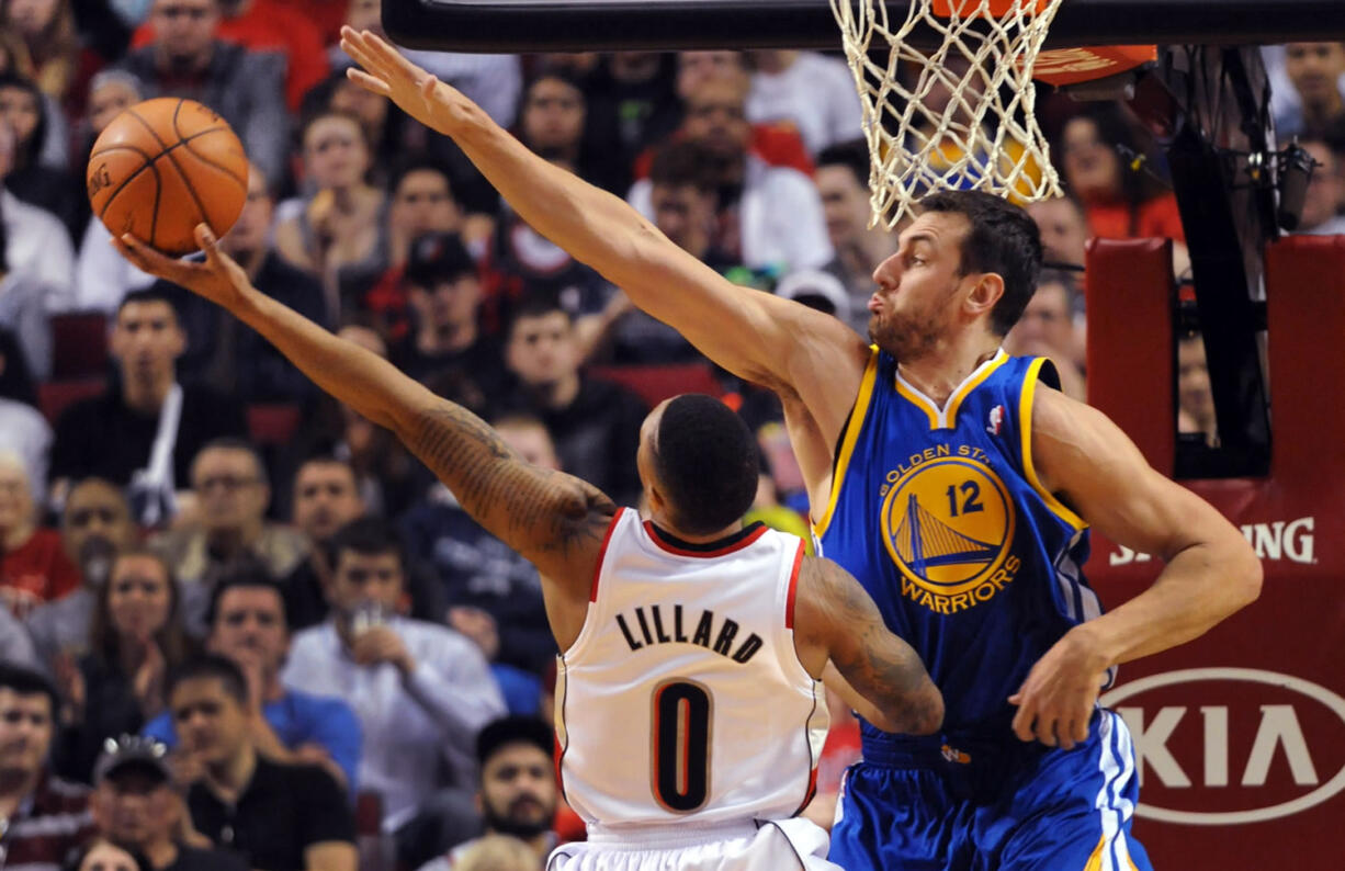 Portland Trail Blazers guard Damian Lillard (0) drives to the basket on Golden State Warriors center Andrew Bogut (12) during the first half Sunday.