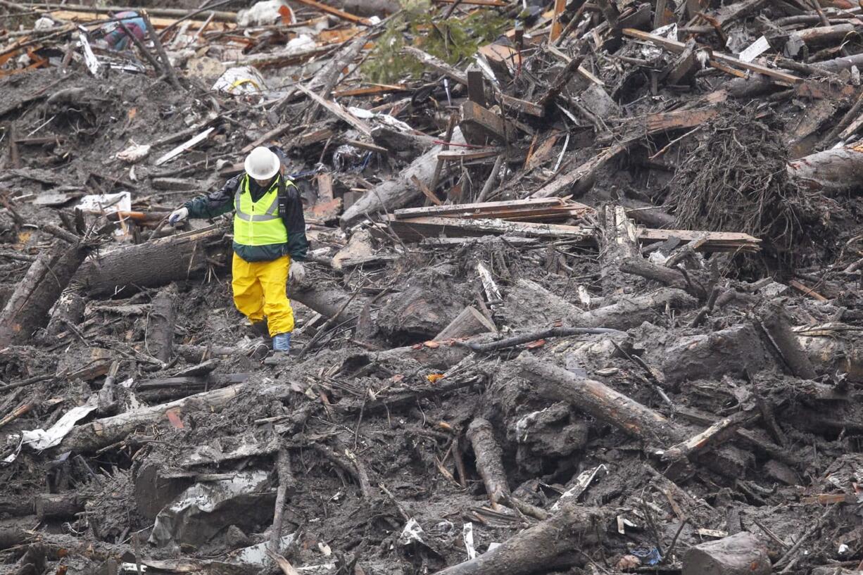 A searcher walks through debris at the scene of a deadly mudslide Saturday in Oso.