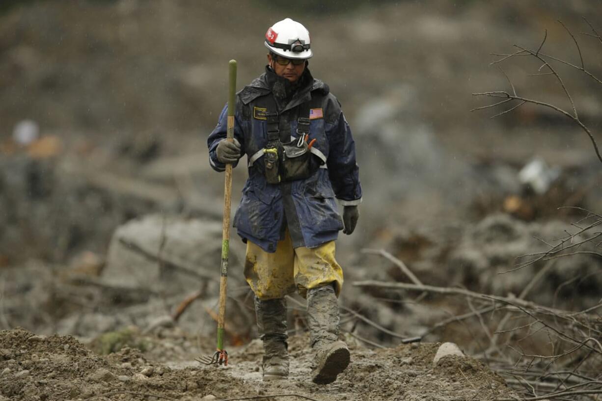 A search worker walks with a tool Wednesday as the search continues for the remaining missing victims of the massive deadly mudslide that hit the community of Oso.