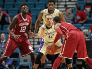 Washington's Andrew Andrews (12) guards Oklahoma's Isaiah Cousins, right, during the first half Saturday, Dec. 20, 2014, in Las Vegas. Washington won 69-67.