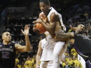 Oregon's Damyean Dotson, center, comes down with a rebound against Washington's Andrew Andrews, left, and Desmond Simmons during the second half an NCAA college basketball game in Eugene, Ore., on Wednesday, Feb. 19, 2014. Oregon won 78-71.