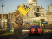 An ILWU local 4 supporter holds a sign outside the main gate to United Grain as a vehicle enters May 1 in Vancouver.