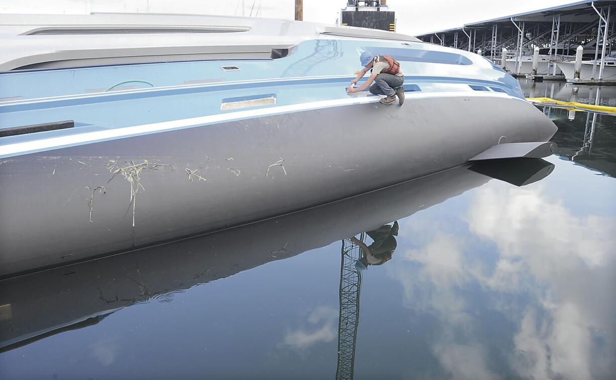 A salvage worker seals window openings on an overturned yacht Monday near Anacortes.