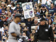 A fan pays tribute to New York Yankees' Derek Jeter as Jeter, left, stands on first base in the first inning of a baseball game against the Seattle Mariners on Thursday in Seattle.
