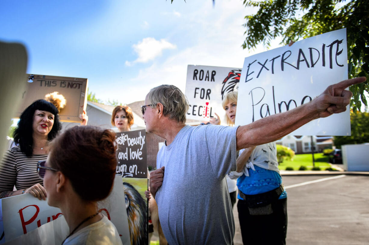 Demonstrators heckled one of Walter Palmer's patients, Thomas Dressel, right, who paused to speak to the media, outside Palmer's dental practice Tuesday in Bloomington, Minn.  One said &quot;I bet he has a confederate flag in his car window.&quot;  He pointed out that he did not. Palmer, after weeks out of the public eye, was the subject of an international uproar after he was identified as the hunter who killed the famous lion Cecil, in Zimbabwe.