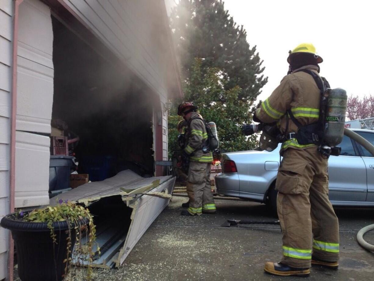 Firefighters from Clark County Fire District 3 assist crews from Clark County Fire &amp; Rescue during a garage fire Saturday at a home at 1705 N.W. Fourth Ave.