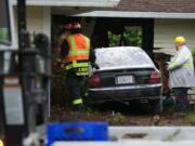 Crews work to remove a car that plowed into an east Vancouver house in the early morning hours on Wednesday, June 18, 2014.