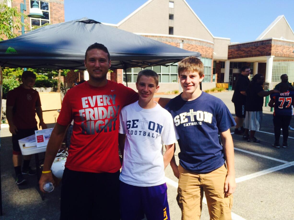 Event organizer Nolan Henry (left) with volunteers with Tristin Ryan and Aiden Ryan, who were among the Seton Catholic football players who assisted with the Clark County Youth Football Food Drive.