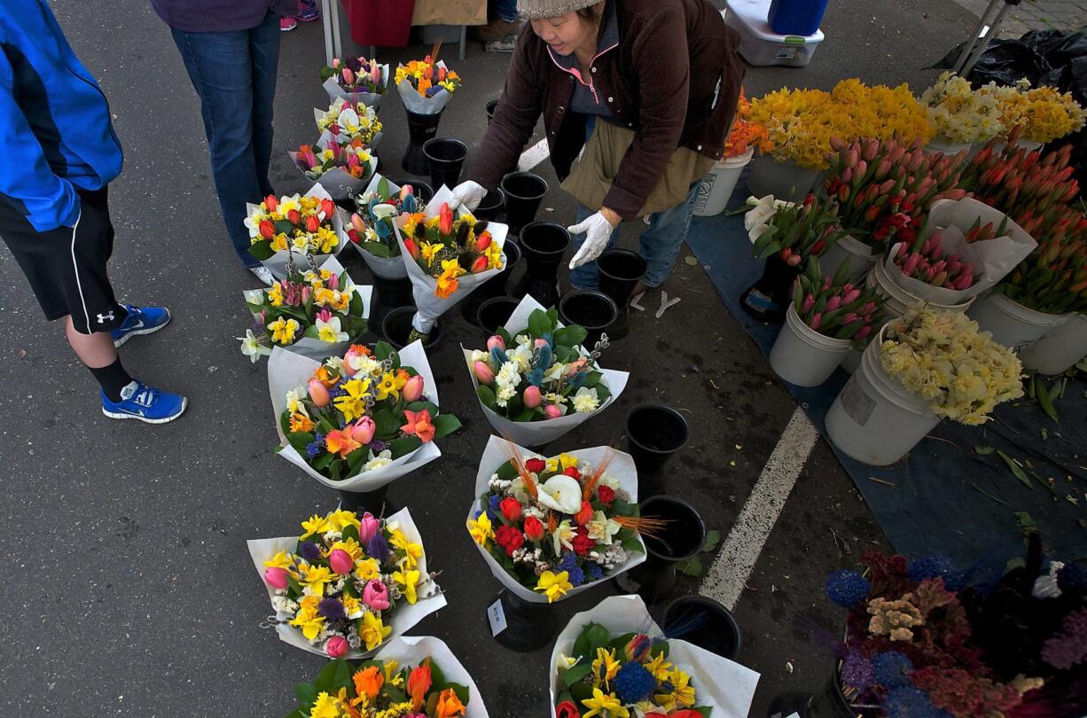 Kia Lor, of C&amp;K's Flower Garden, grabs a bouquet for a customer during the opening weekend of the Vancouver Farmers Market, which is celebrating its 25th season this year.