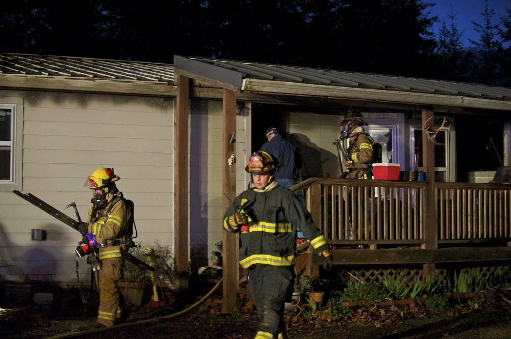 Firefighters mop up after extinguishing a fire Wednesday evening that started in the kitchen of a double-wide manufactured home near Dollars Corner.