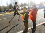 Volunteers offer water to runner Johnson Lee as he passes in the annual Vancouver Lake Half Marathon on Sunday.