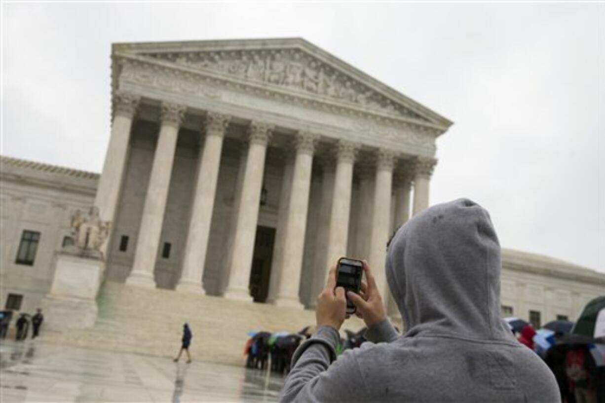 A Supreme Court visitor using his cellphone to take a photo of the court in Washington. A unanimous Supreme Court says police may not generally search the cellphones of people they arrest without first getting search warrants.