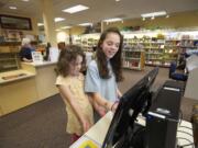 Aviela Olson, 5, left, and her sister Madeleine Olson, 10, check out books at the Ridgefield library on March 14.