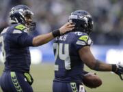 Seattle Seahawks running back Marshawn Lynch, right, gets a pat on the back from quarterback Russell Wilson as he goes to shake the hand of another teammate after scoring a touchdown against St. Louis Rams on Dec.