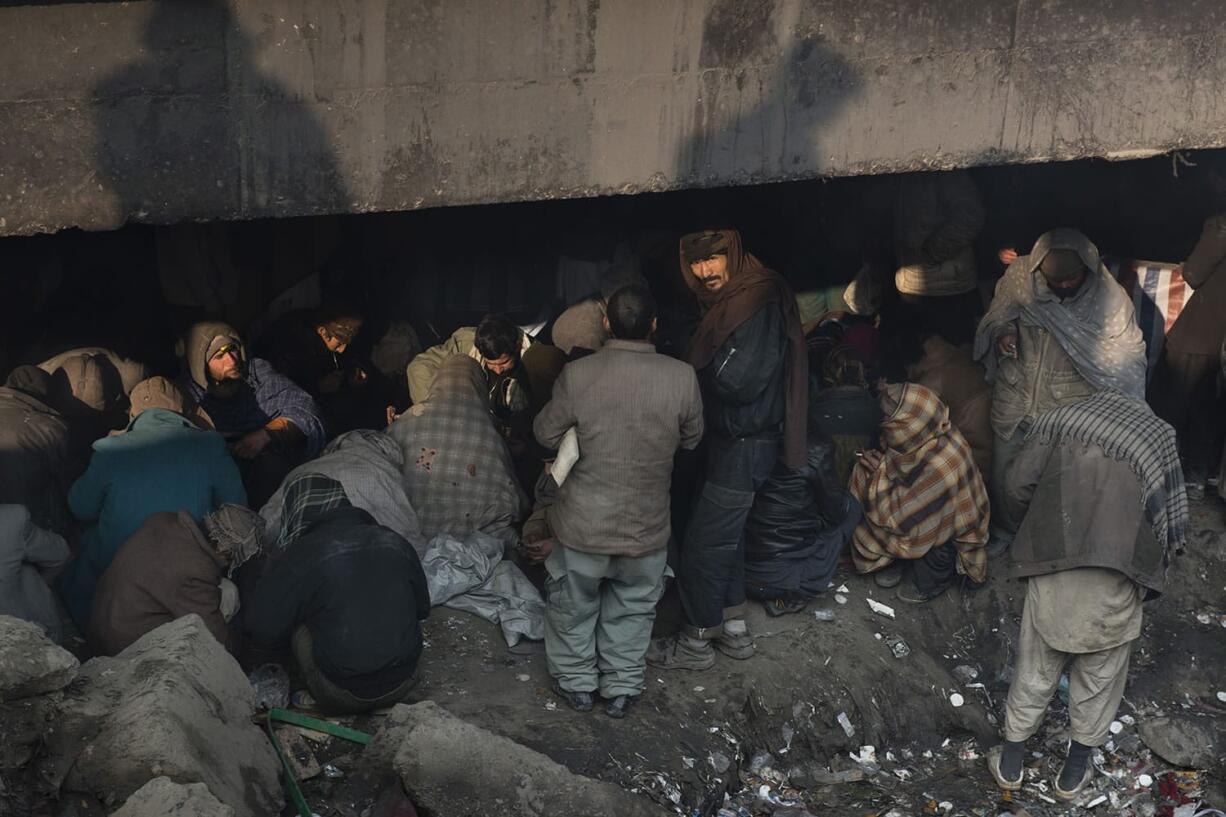 Kiana Hayeri/The Washington Post
Bystanders watch as addicts use heroin below the Pule Sukhta, or burnt bridge), on Tuesday in Kabul, Afghanistan. UN officials estimate there are 1.6 million drug users in Afghanistan, about 5 percent of the population.