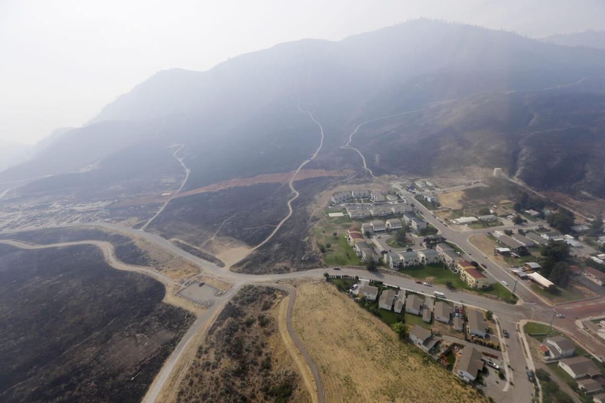 Scorched hills surround a housing development that survived a wildfire days earlier Aug. 27 near Chelan. The complex of fires that burned throughout the area is the largest in state history.