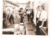 With pressmen and a crowd, Don Campbell, Morrie Shore and Jack Campbell watch the first run on the new Goss Metro Press.