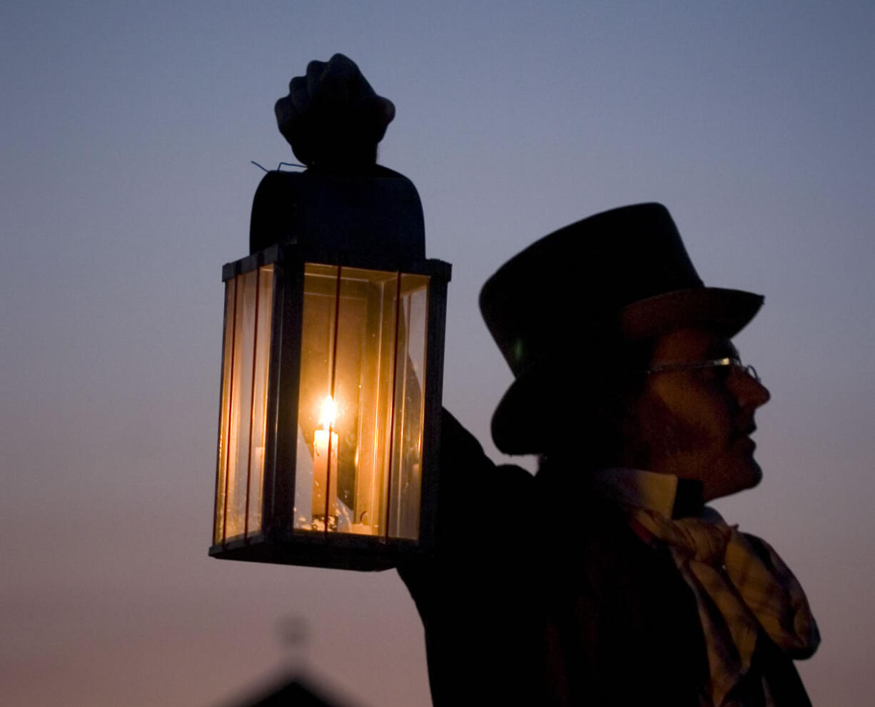 Dressed in period garb, Greg Shine, chief ranger and historian at Fort Vancouver, holds a lantern during a candlelight tour.