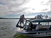 Clark County Sheriff&#039;s deputy Kevin Gadaire climbs back inside the marine patrol boat while patrolling the Columbia River in 2014.