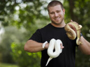 P.J. Suss holds an ivory ball python, left, and a Champagne ball python in Orlando, Fla. Suss, who raises and breeds ball pythons as a business, says he doesn&#039;t think that a snake can be a service animal.