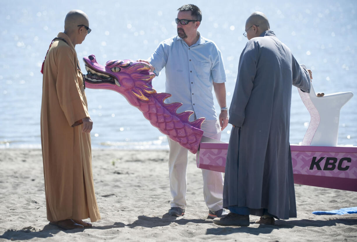 Jeff Campbell, owner of Double Fifth Dragon Boating, attaches the removable head onto the new Kearney Breast Center dragon boat that was unveiled July 30. Buddhist monks performed a blessing ceremony for the boat.