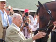 Veterinarian William McGee, 98, who has seen six Triple Crown winners, pats 2015 Triple Crowner American Pharoah (held by the hand of trainer Bob Baffert) at his June 12, 2015, morning jog at Churchill Downs in Louisville, Ky. As a boy, McGee attended what then was Shumway Junior High in Vancouver.