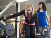 Breast cancer survivor Jill Barr, under the observation of physical therapist Joyce Masters, practices strength-building exercises.