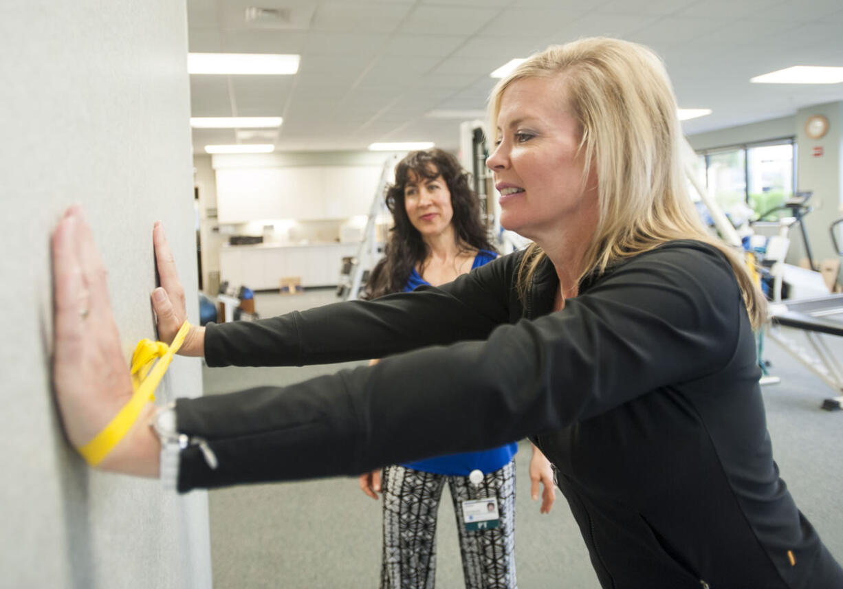 Breast cancer survivor Jill Barr performs a stretching exercise under the observation of physical therapist Joyce Masters. Stretching helps restore range of motion to post-surgical patients.