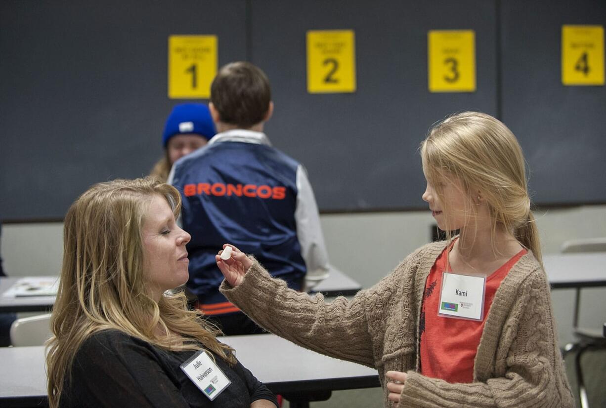 Julie Halvorson, left, closes her eyes as she attempts to guess the vegetable fed to her by her daughter, Kami, 10, during a FoodMania class Wednesday evening at CASEE in Brush Prairie. The vegetable tasting event -- the mystery veggie was a radish -- was one of several activities the children and parents participated in during the two-hour class.