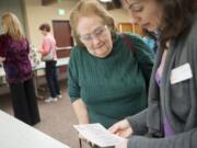 Sharon Gutz, left, gets some help reading small type from Stephanie Barr as Gutz participates in a workshop at the YWCA on Tuesday evening. The event puts people in the shoes of domestic violence victims.