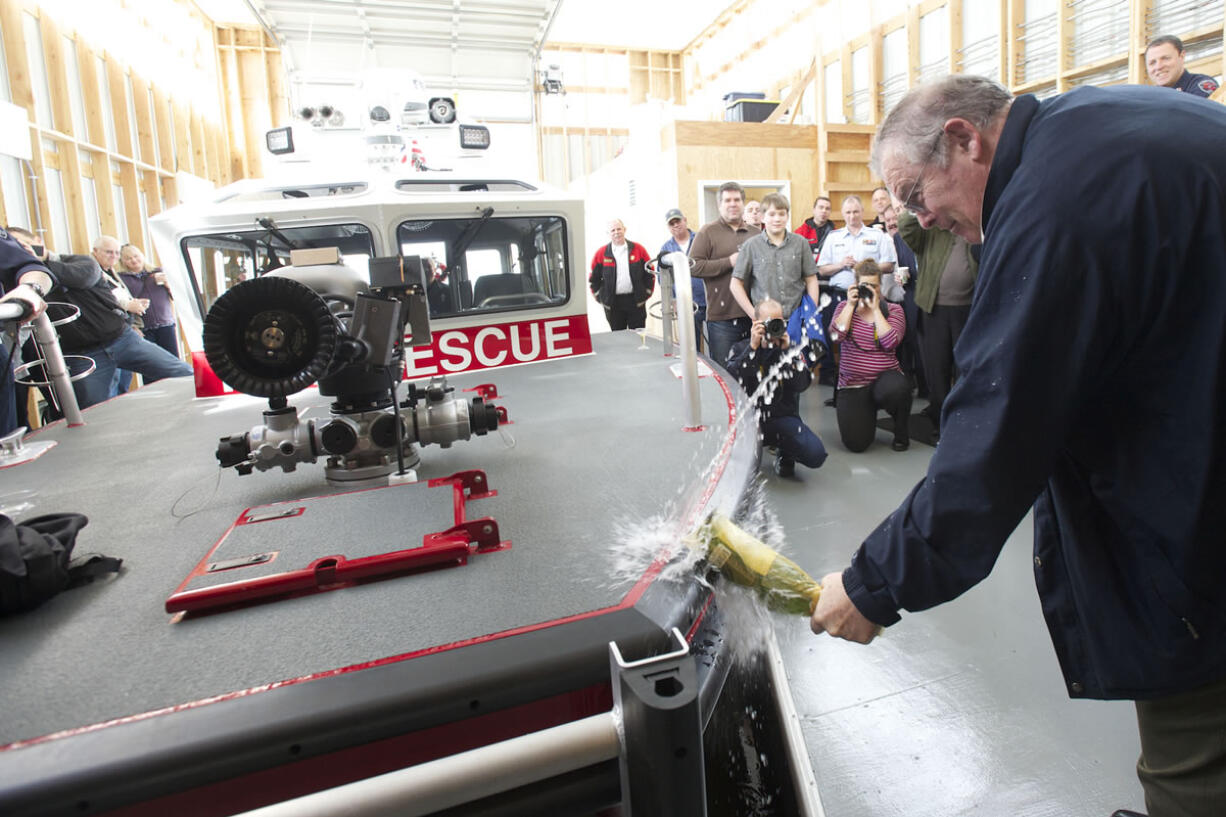 Bruce Firstenburg christens Clark County Fire &amp; Rescue's new boat during a ceremony at the Ridgefield Marina on Friday.
