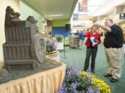 Visitors look at a creation made by sand sculptor Bert Adams of Yacolt. His rendition of Portland International Airport was unveiled Tuesday in the PDX terminal. The Port of Portland, Travel Portland officials, airport employees and visitors marked the 75th anniversary of PDX Tuesday with art displays and cupcakes.