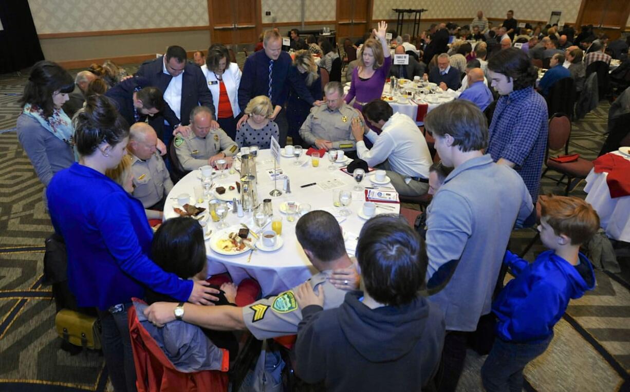 Guests pray over Clark County Sheriff Chuck Atkins and some of his deputies during the prayer breakfast, which recognized community leaders and first responders.