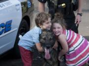 Jack Curtis, 6, left, and his sister, Emma, 4, share a happy moment with police dog Enzo on Wednesday afternoon in southeast Vancouver.