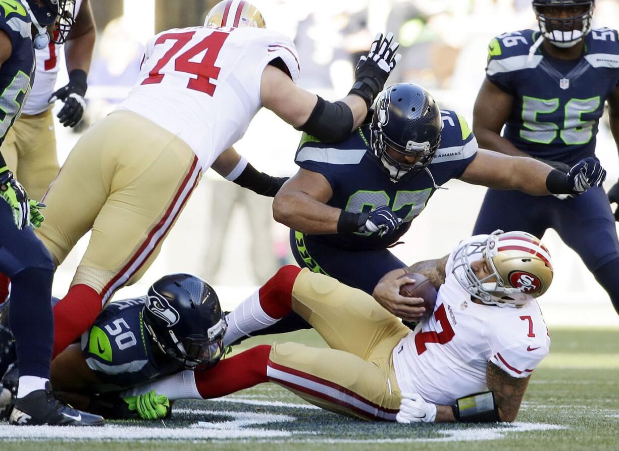 San Francisco 49ers quarterback Colin Kaepernick is sacked by Seattle Seahawks defensive tackle Jordan Hill (97) and outside linebacker K.J. Wright (50) in the first half against the Seattle Seahawks, Sunday, Dec.