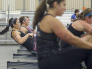 Christine Lum, left, competes in the rowing machine portion of the CrossFit Fort Vancouver Invitational at the Clark County Event Center on Saturday.