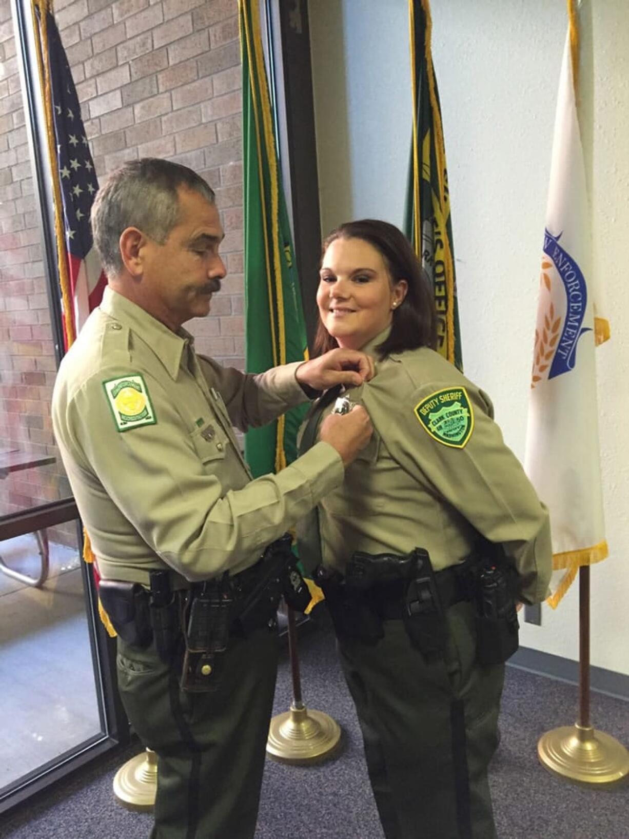 Veteran Clark County Sheriff&#039;s Deputy Greg Chaney pins a deputy&#039;s badge on his niece, Tina Wiggs, at her swearing-in ceremony Thursday. Wiggs was a police officer in the Metropolitan Nashville Police Department for 7 1/2  years before joining the Clark County Sheriff&#039;s Office.